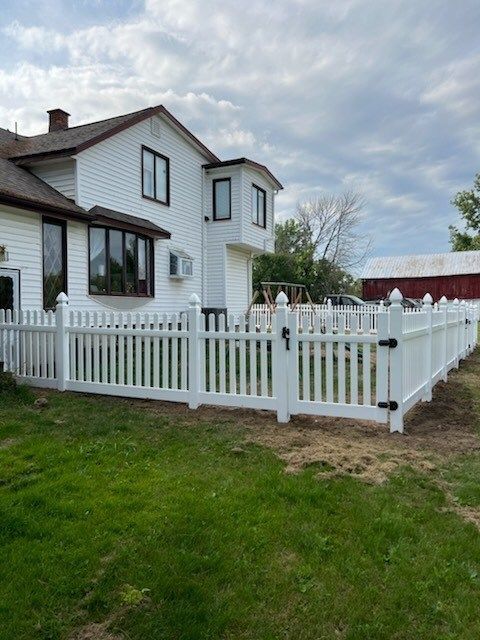 A white picket fence is in front of a white house