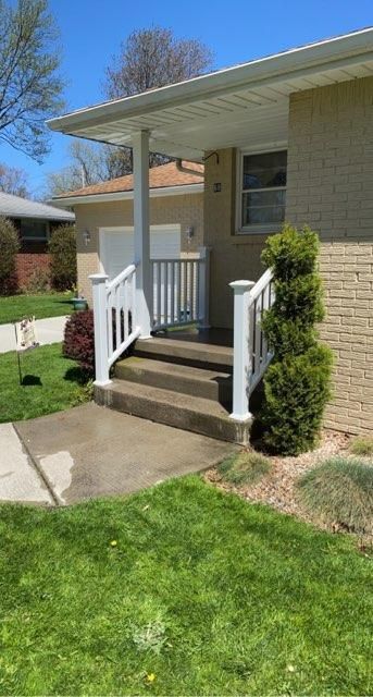 A house with a porch , stairs and a white railing.