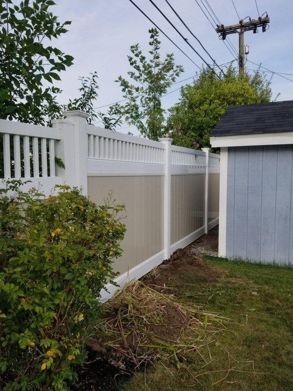 White and tan vinyl fence with a shed in a backyard.