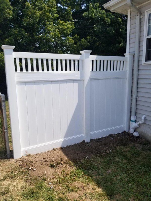 A white vinyl fence is sitting in front of a house.