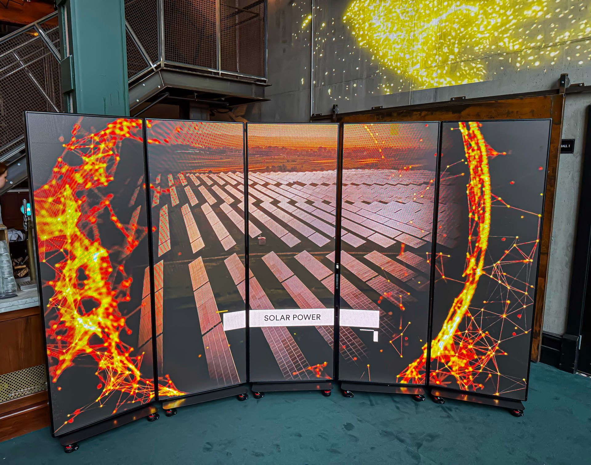 Kaarevat näyttöpaneelit, jotka esittävät aurinkovoimalaa auringonlaskun aikaan, tulisieluisen digitaalisen grafiikan ympäröimänä.