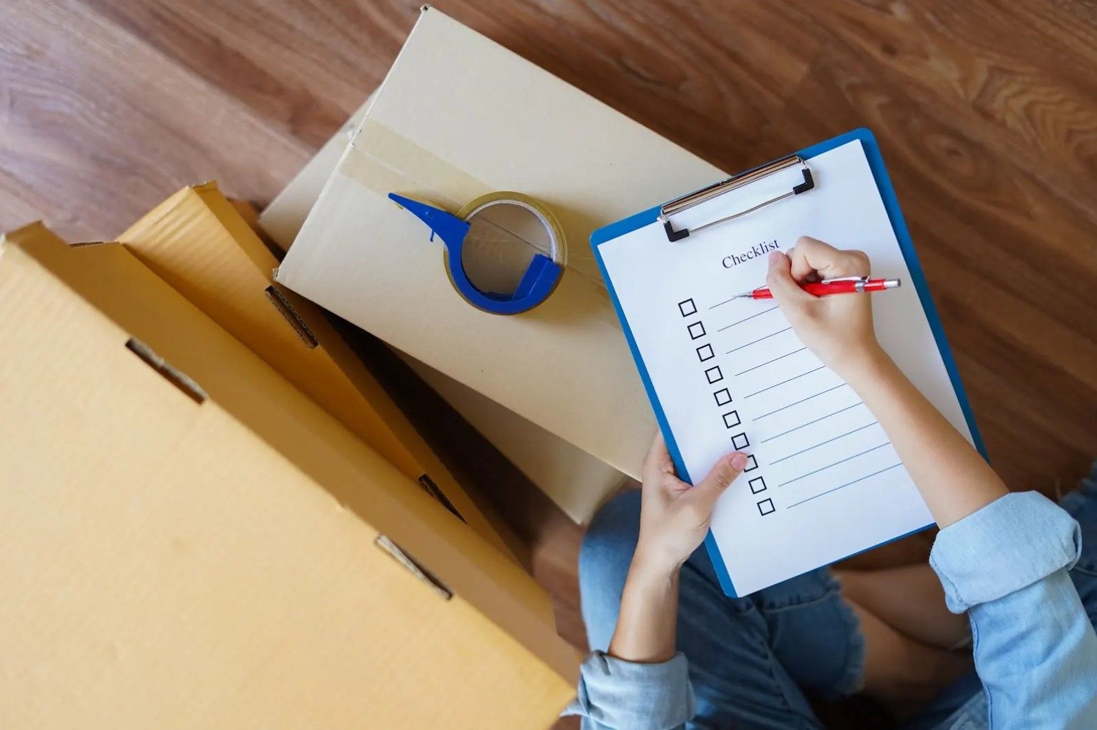 A person is sitting on the floor holding a clipboard and writing on it.