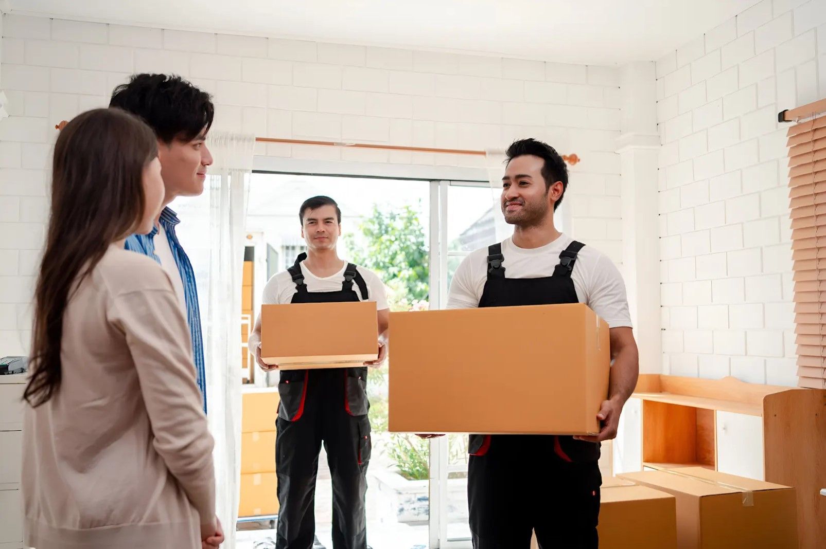 A group of movers are carrying boxes into a house.