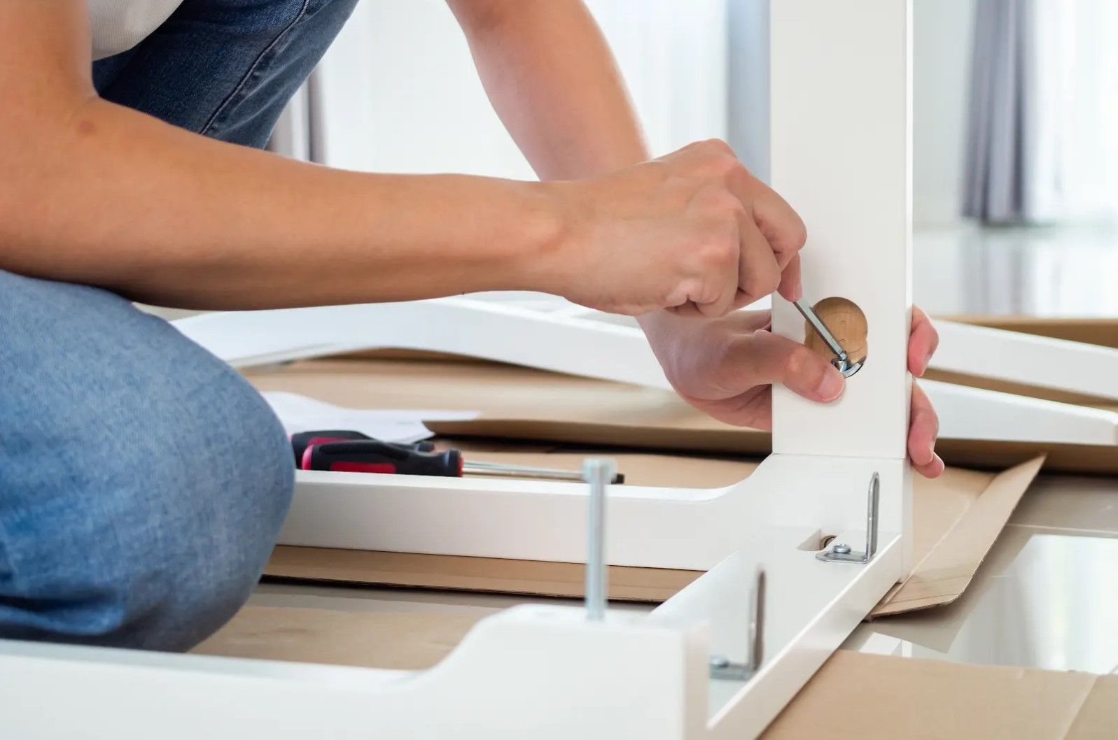 A person is sitting on the floor assembling a table.