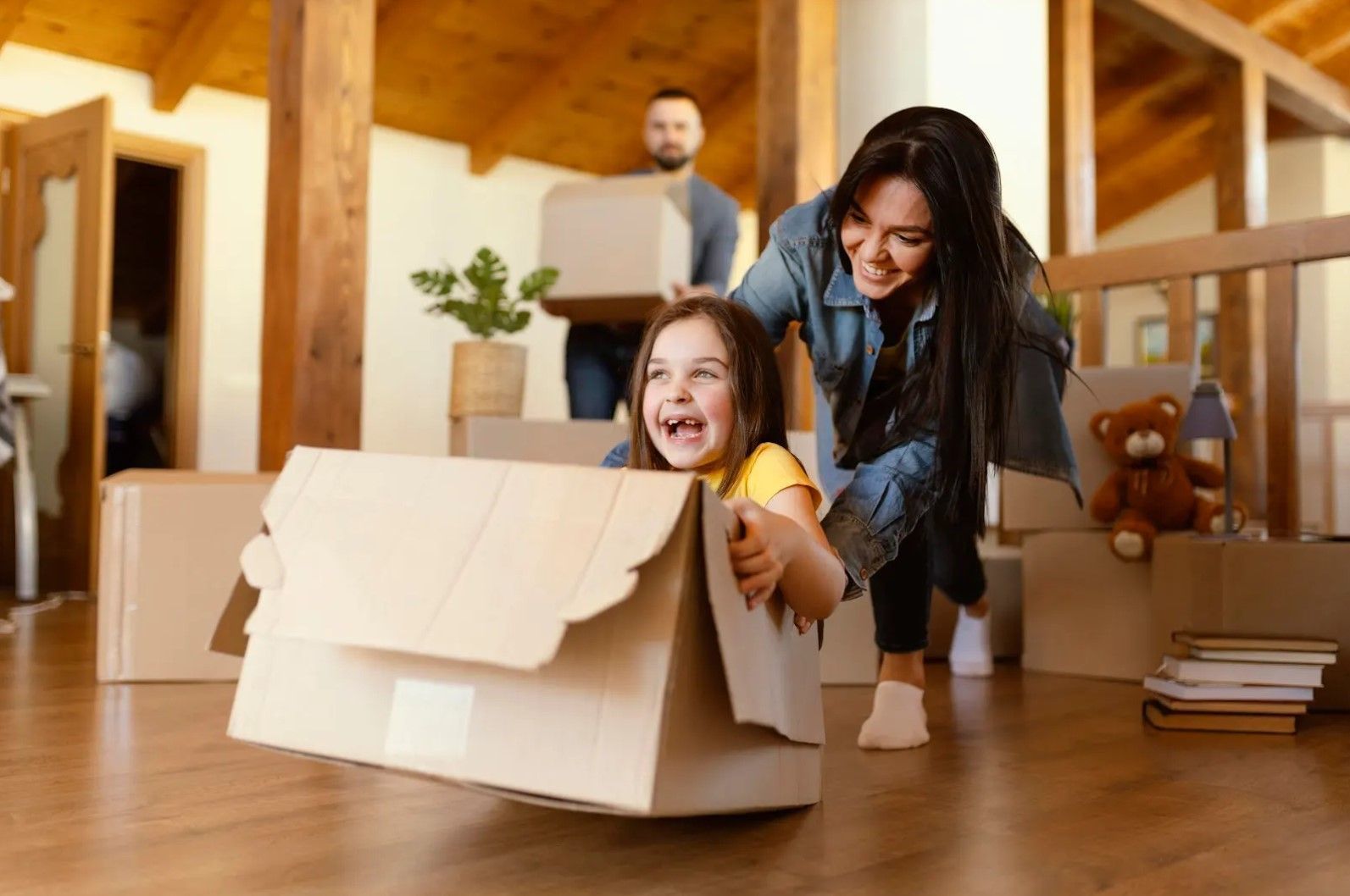 A woman is holding a little girl in a cardboard box.