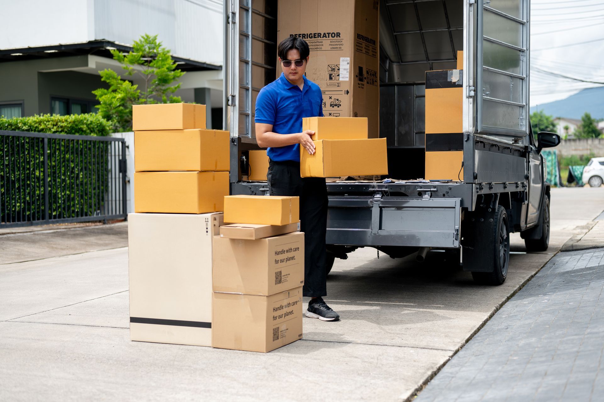 A man is standing in front of a truck filled with boxes.