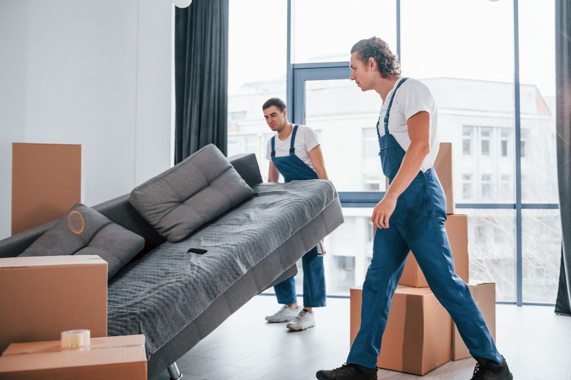 Two men are moving a couch in a living room.