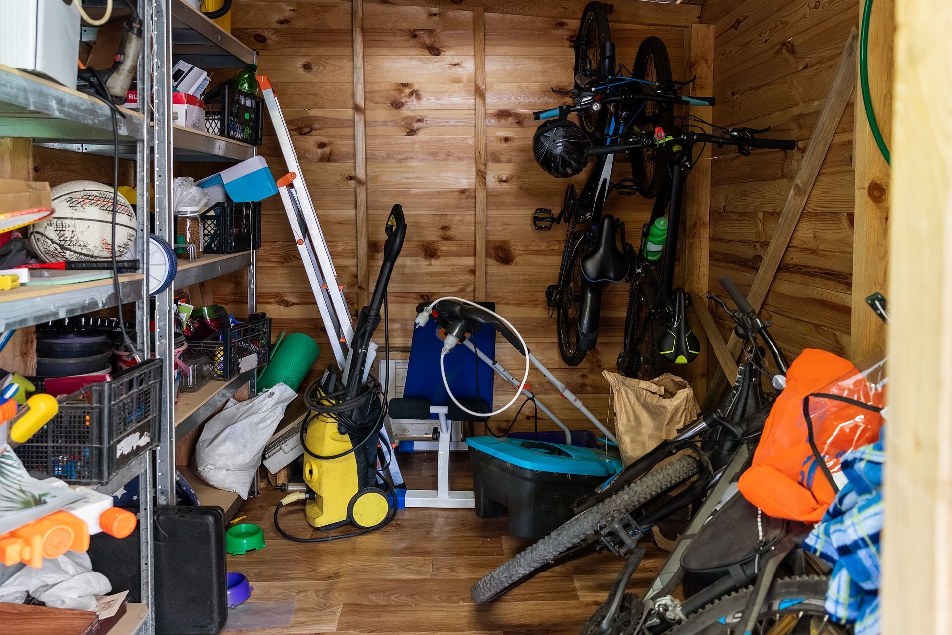 A wooden shed filled with lots of tools and bicycles.