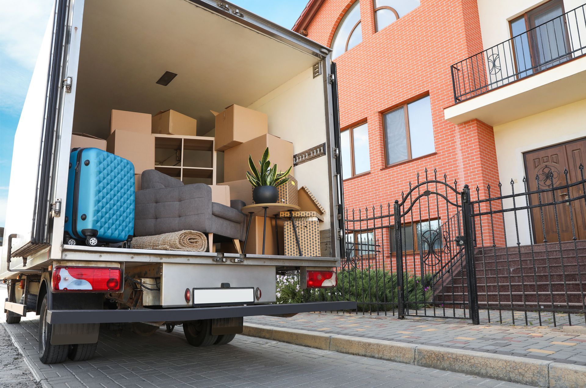 A moving truck is filled with boxes and luggage in front of a house.