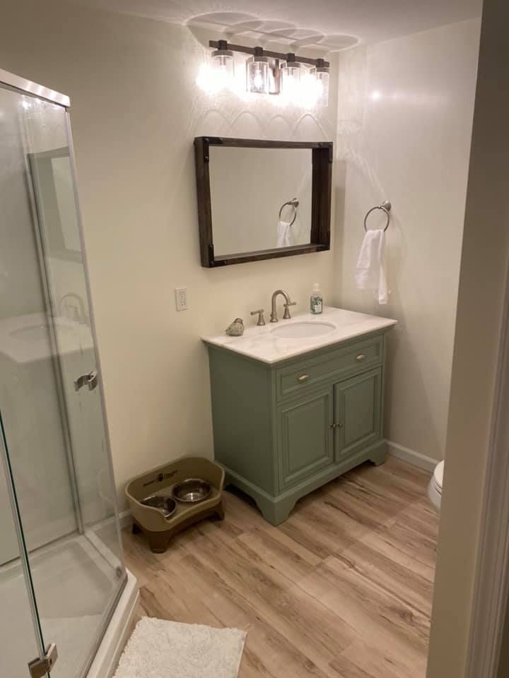 A bathroom with a sink , mirror and shower.