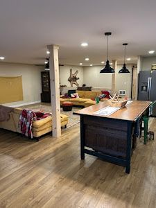 A living room with hardwood floors , a couch , a table and a refrigerator.