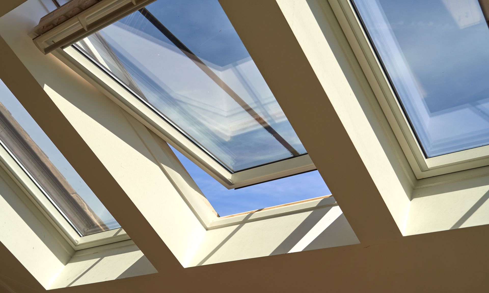 Skylight windows in a slanted ceiling, showing blue sky and sunlight