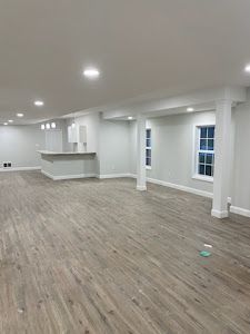 A large empty basement with hardwood floors and white walls.