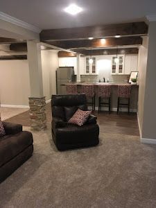 A living room with a couch , chair , and kitchen in the background.