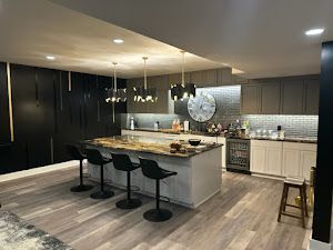 A kitchen with a large island and stools and a clock on the wall.