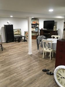 A living room with hardwood floors , a table and chairs , and a clock.