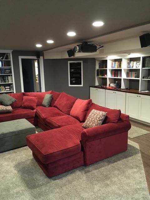 A living room with a red sectional couch and ottoman
