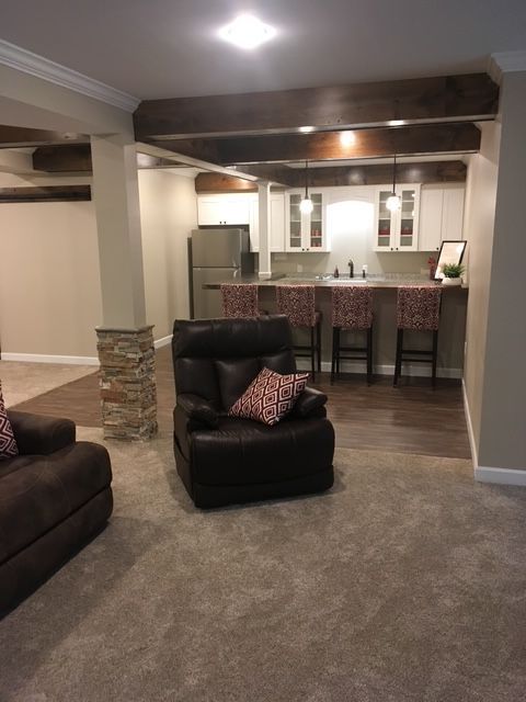 A living room with a chair and a couch and a kitchen in the background