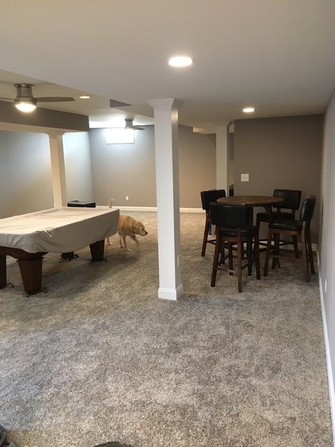 A basement with a pool table , tables and chairs.