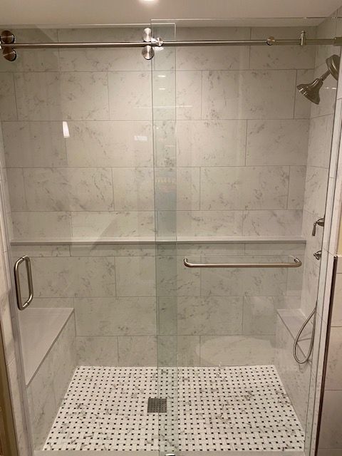 A bathroom with a walk in shower with a sliding glass door.
