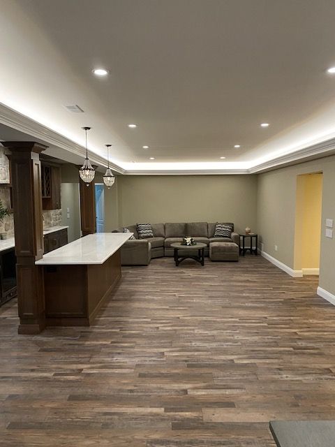 A living room with hardwood floors , a couch , a table , and a kitchen.