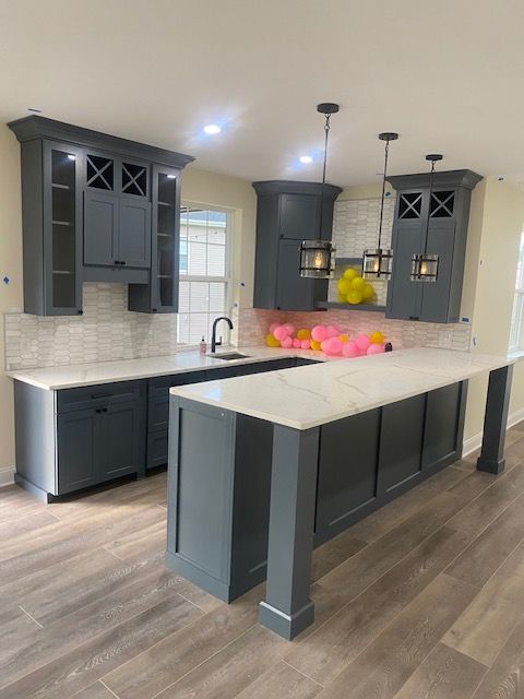 A kitchen with gray cabinets and white counter tops