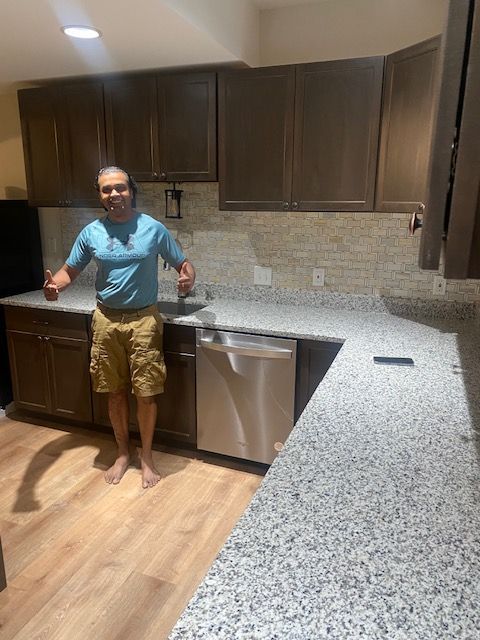 A man is standing in a kitchen with a stainless steel dishwasher.