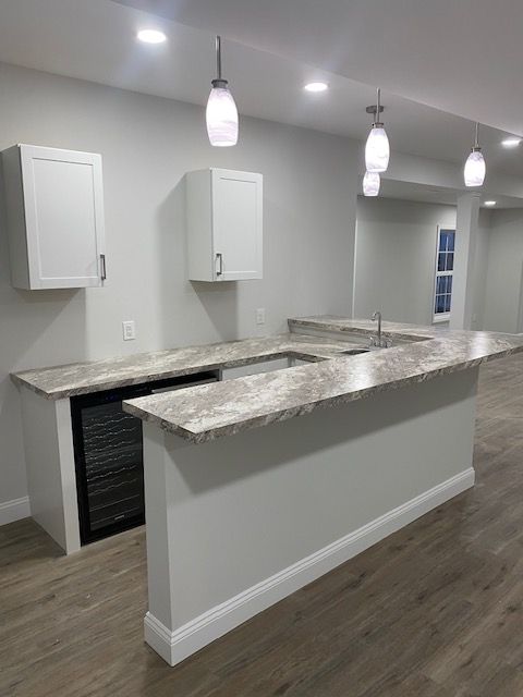 A kitchen with granite counter tops , white cabinets , and a refrigerator.