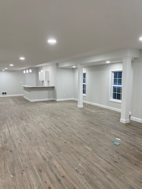 An empty basement with hardwood floors and white walls.
