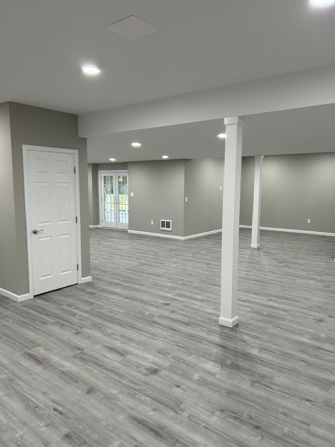 An empty basement with hardwood floors and gray walls.