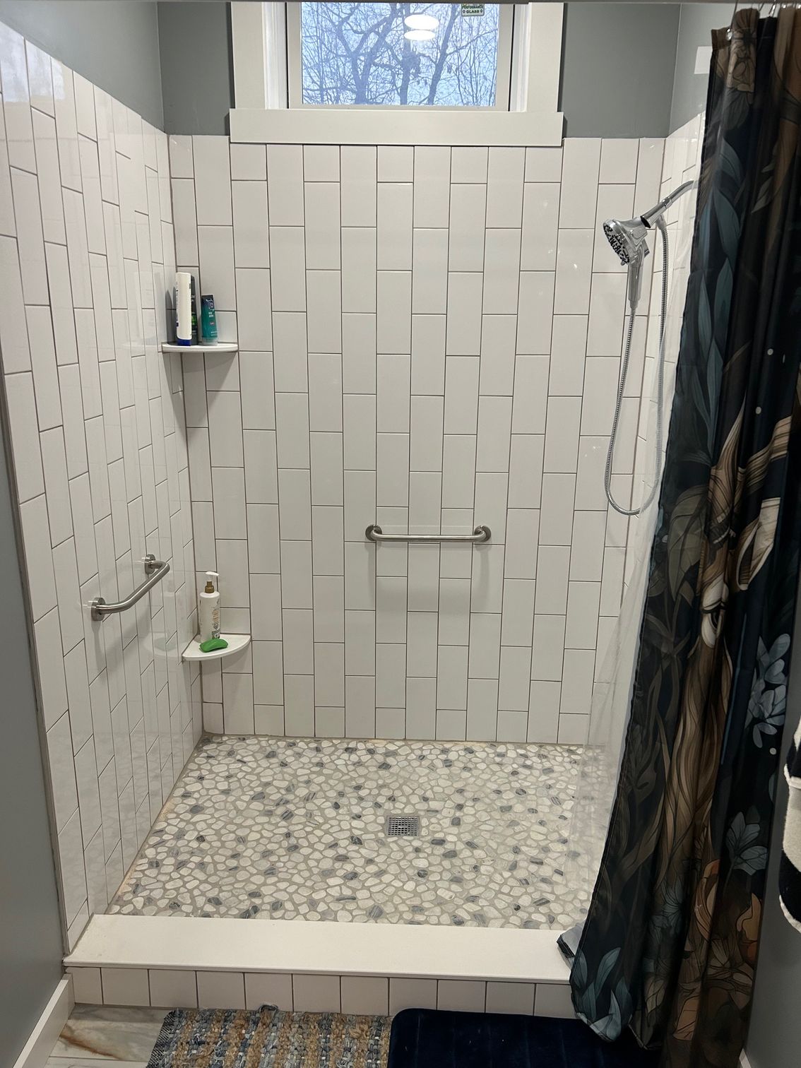 A bathroom with a walk in shower and a window.