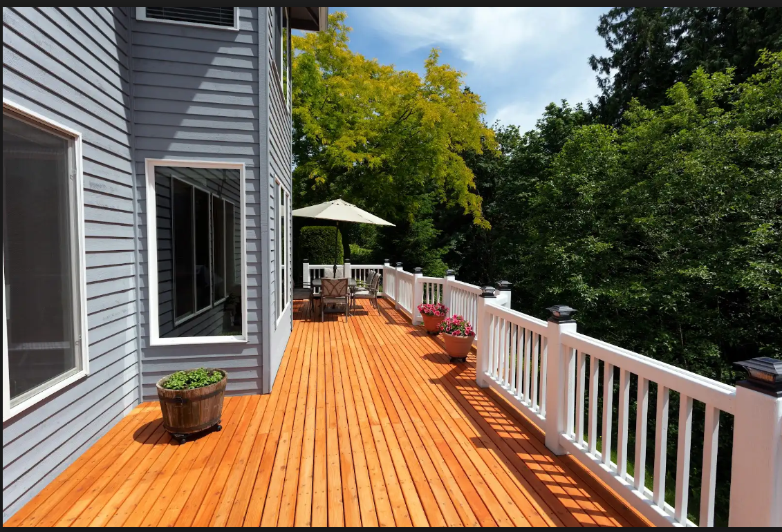 A large wooden deck with a white railing and umbrellas