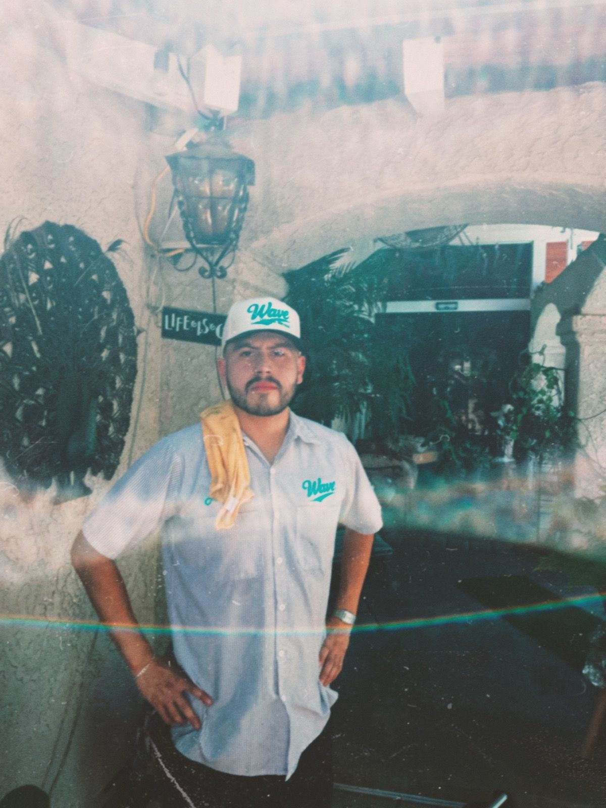 Mop cleaning a shiny brown wooden floor, close up. Green handle, blue pad with tan fringe.