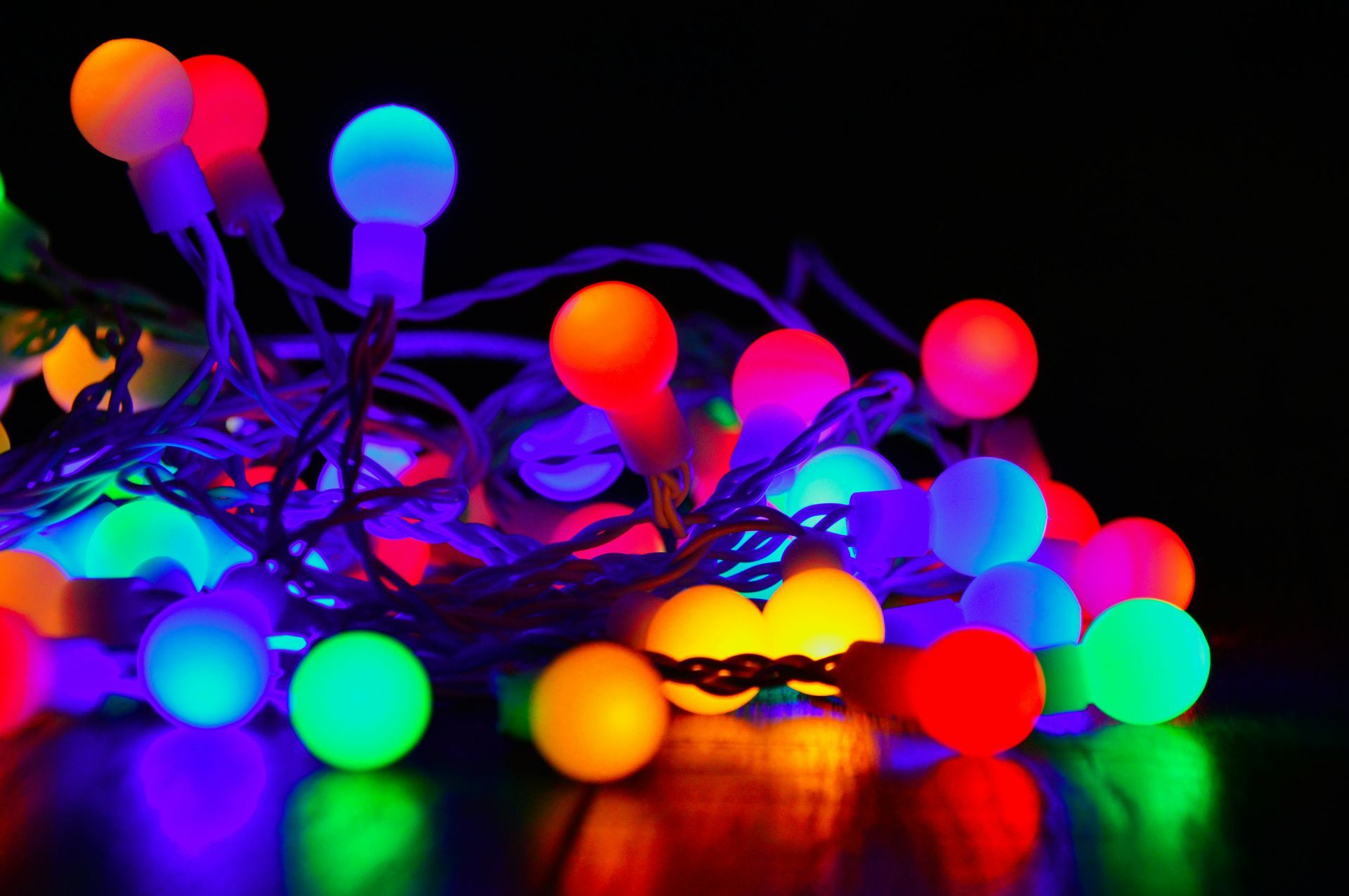String of colorful round LED lights on a black background, glowing in various shades.