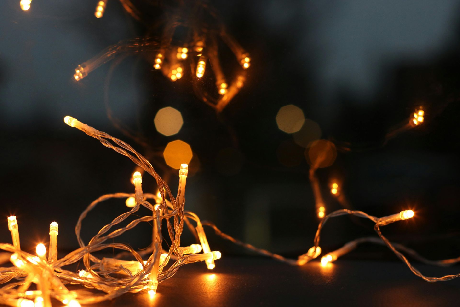 Twinkling string lights with a warm glow, against a dark blurred background.