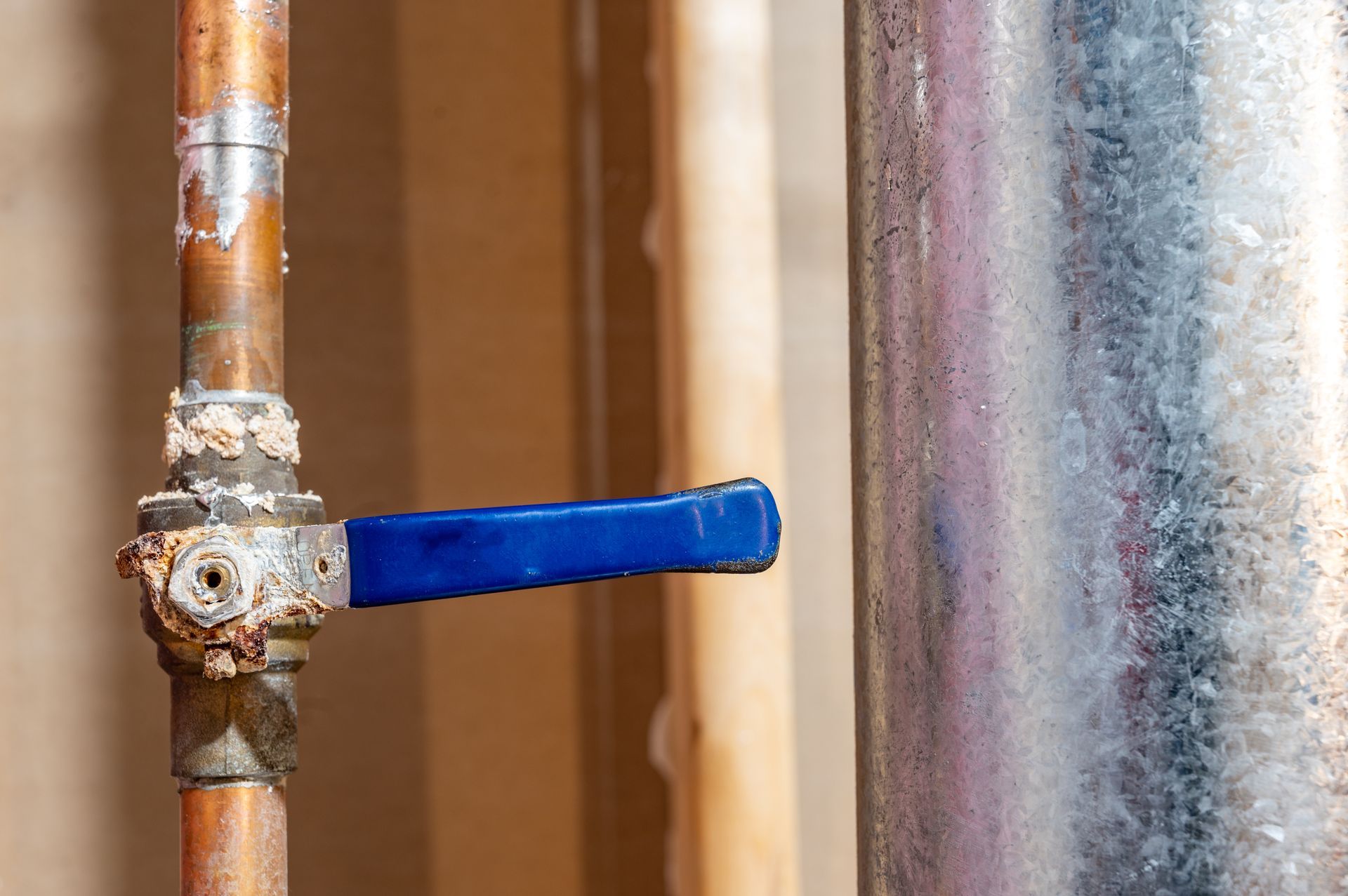 Copper pipe with blue valve and a galvanized pipe next to it.