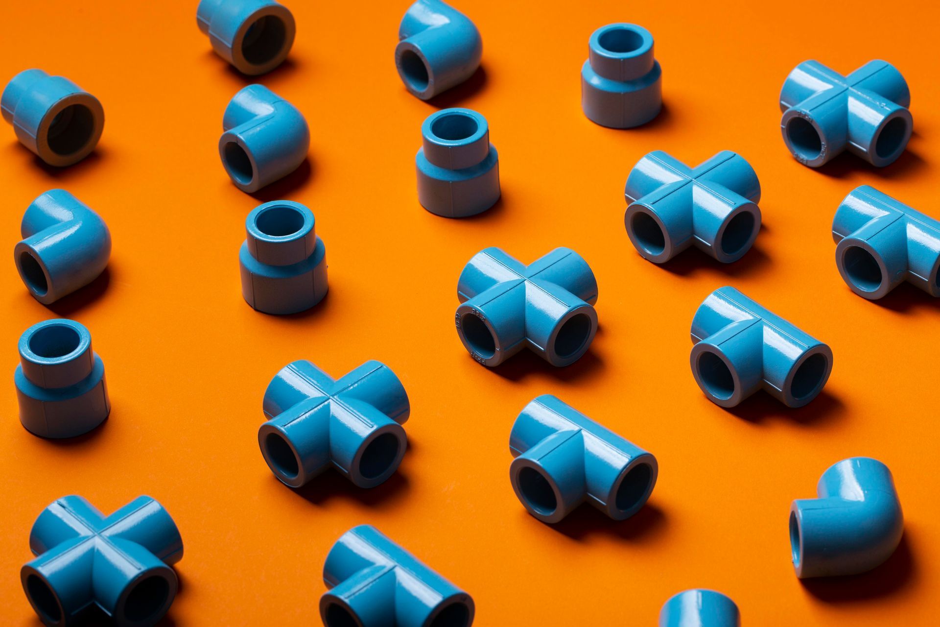 Blue PVC pipe fittings scattered on an orange surface.