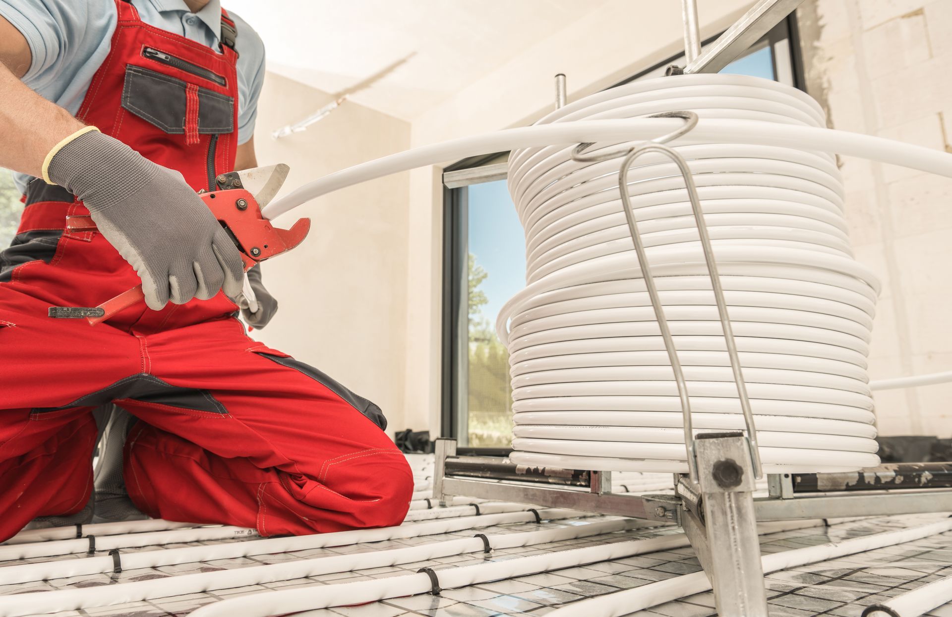 Worker in red safety gear beside a large coiled white hose or cable