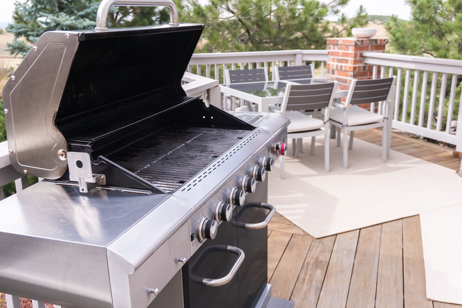 A grill is sitting on a wooden deck with the lid open.