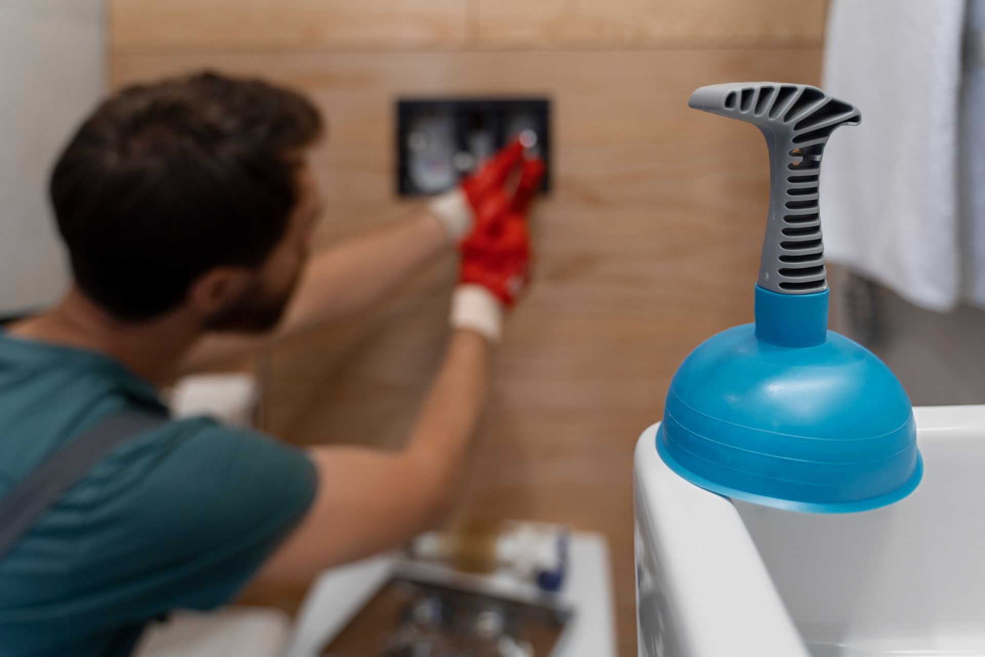 A man is cleaning a bathroom sink with a plunger.