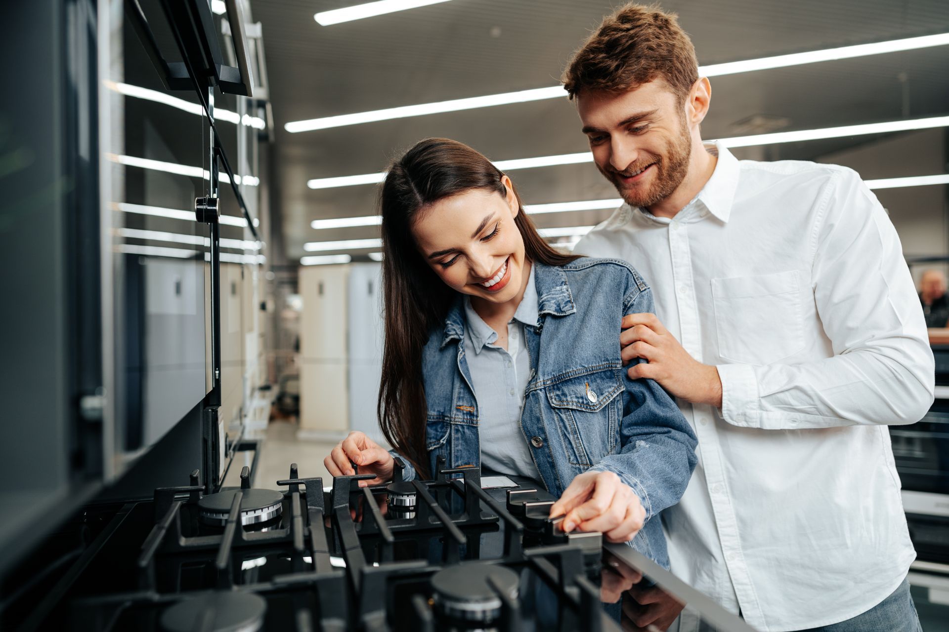 A man and a woman are looking at a gas stove in a kitchen.