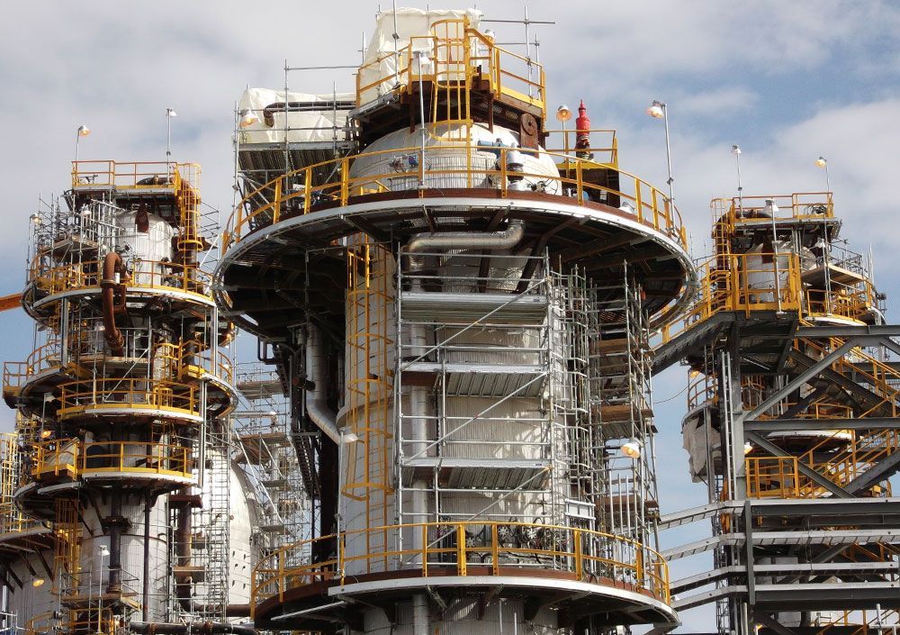 Industrial structure under construction with scaffolding and workers on a large concrete tower