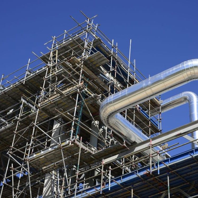 Industrial scaffolding around a large metal structure against a clear blue sky