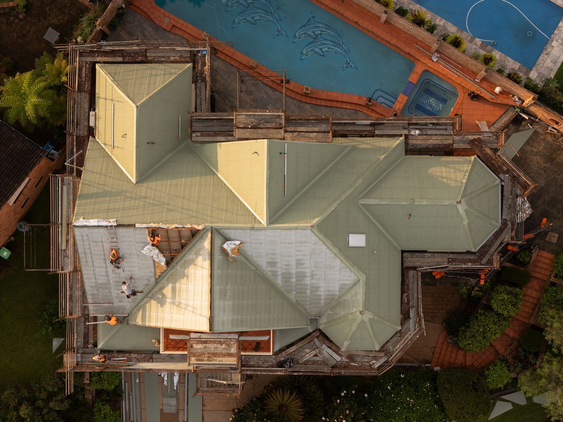 Aerial shot of a damaged roof with people working on it — GT Metal Roofing Solutions in Wollongong, NSW
