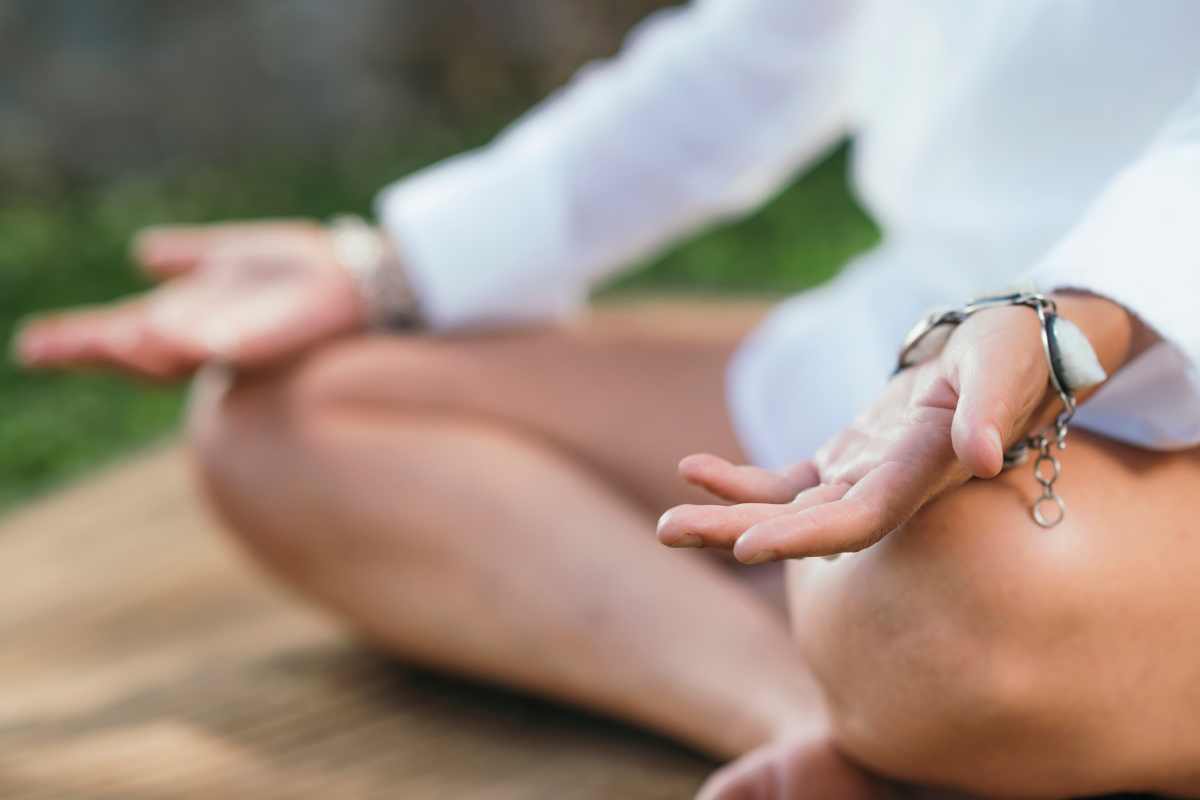 A woman is sitting in a lotus position on a yoga mat.