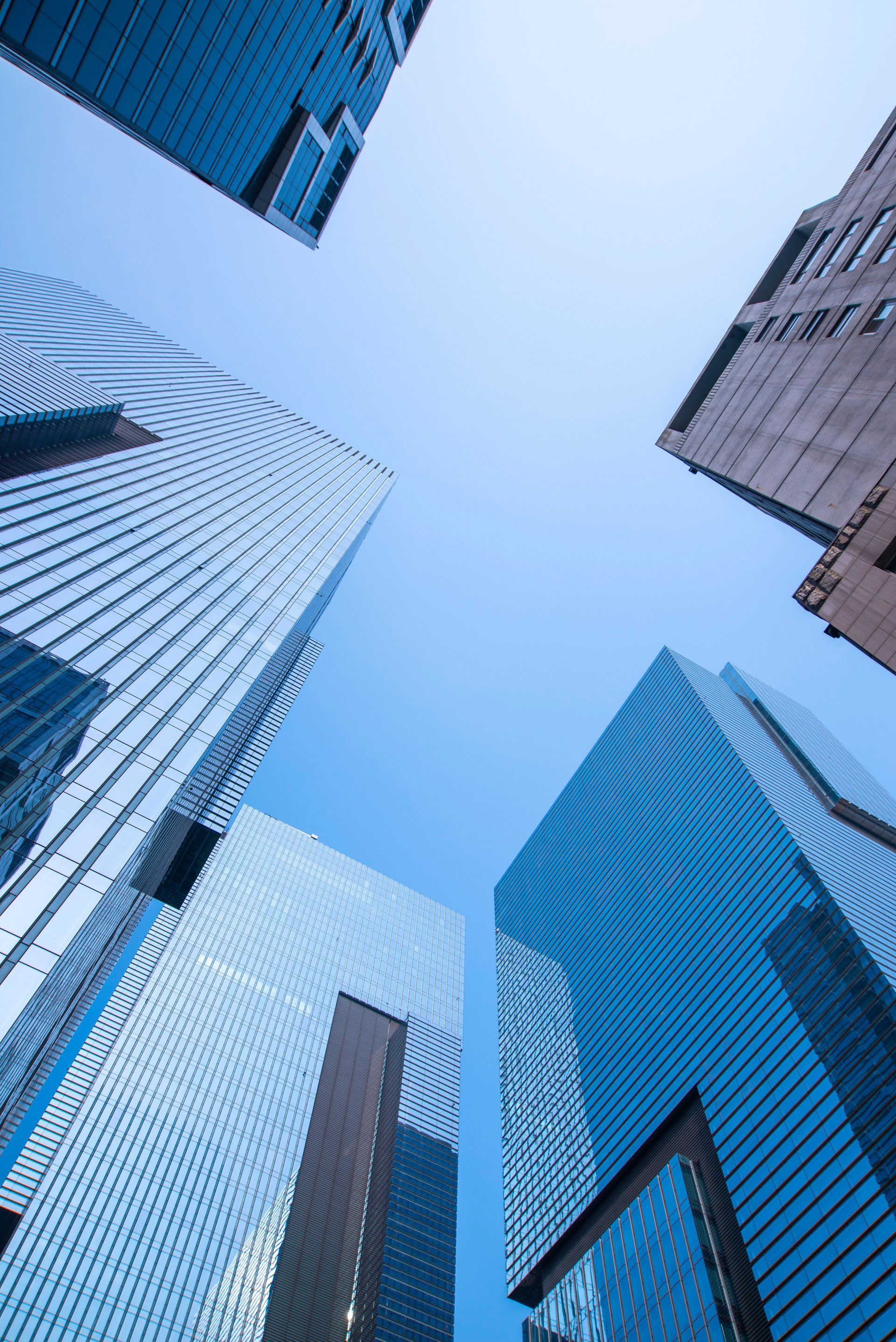 Looking up at a group of tall buildings with a blue sky in the background