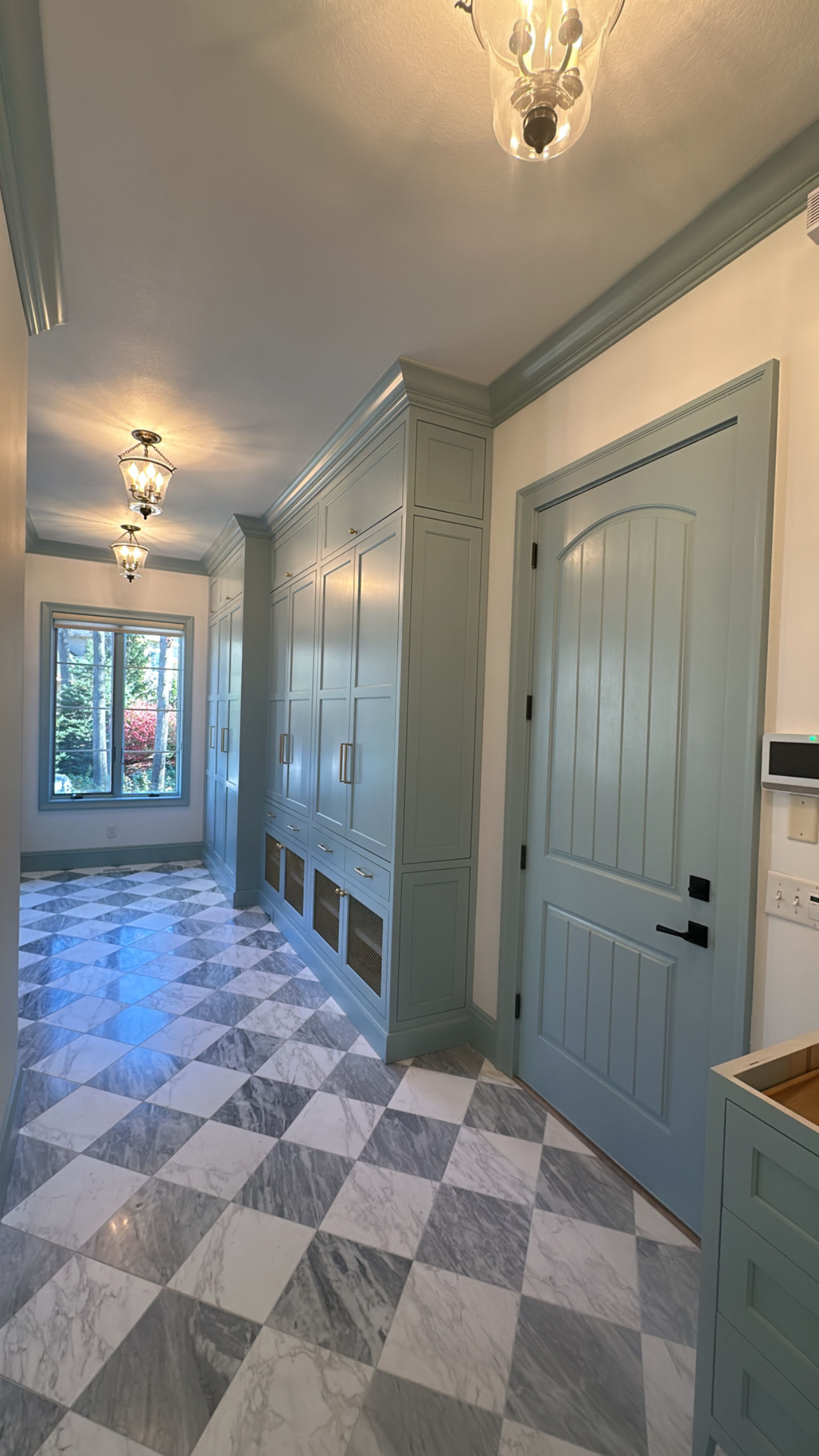 Hallway with blue cabinets, checkered floor, and arched door.