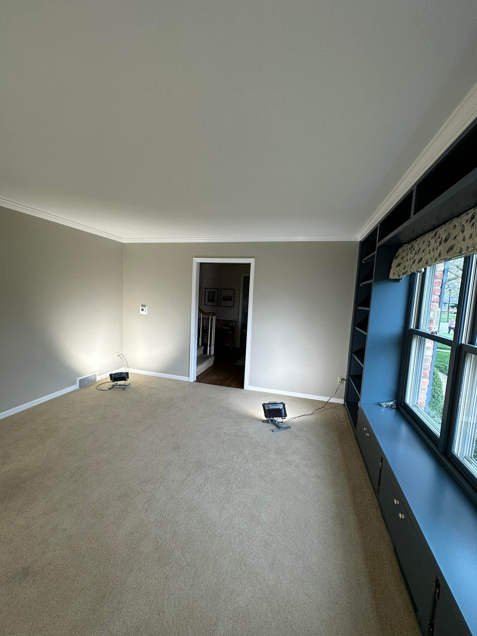 Empty room with neutral walls, carpet, and a large window with built-in storage.