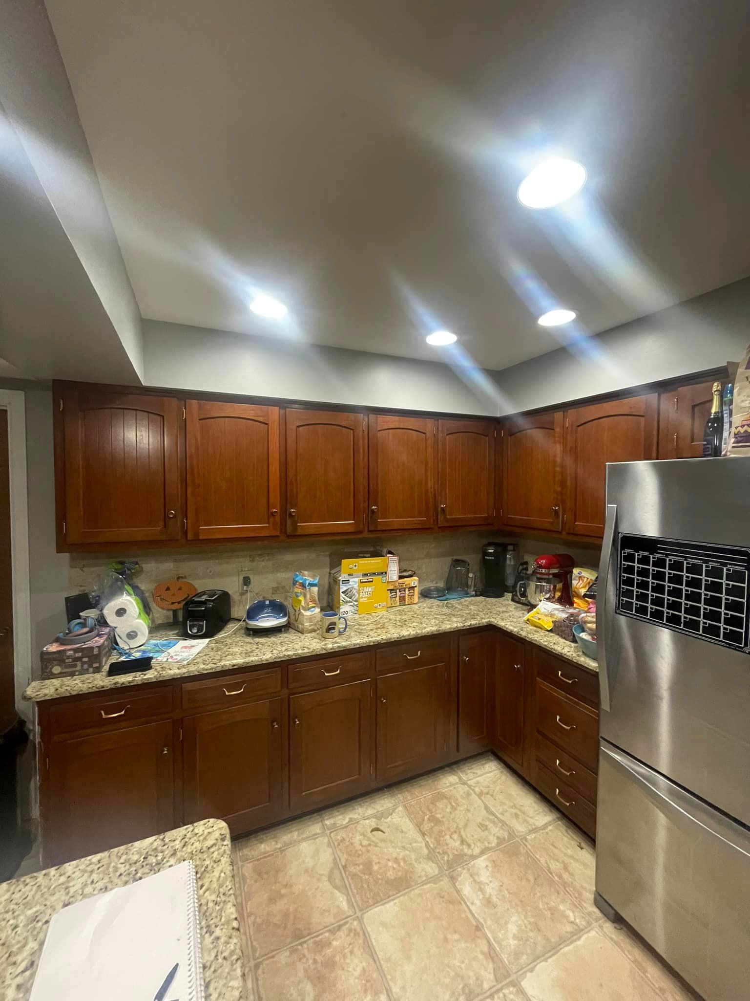 Kitchen with dark wood cabinets, granite countertops, and stainless steel refrigerator.