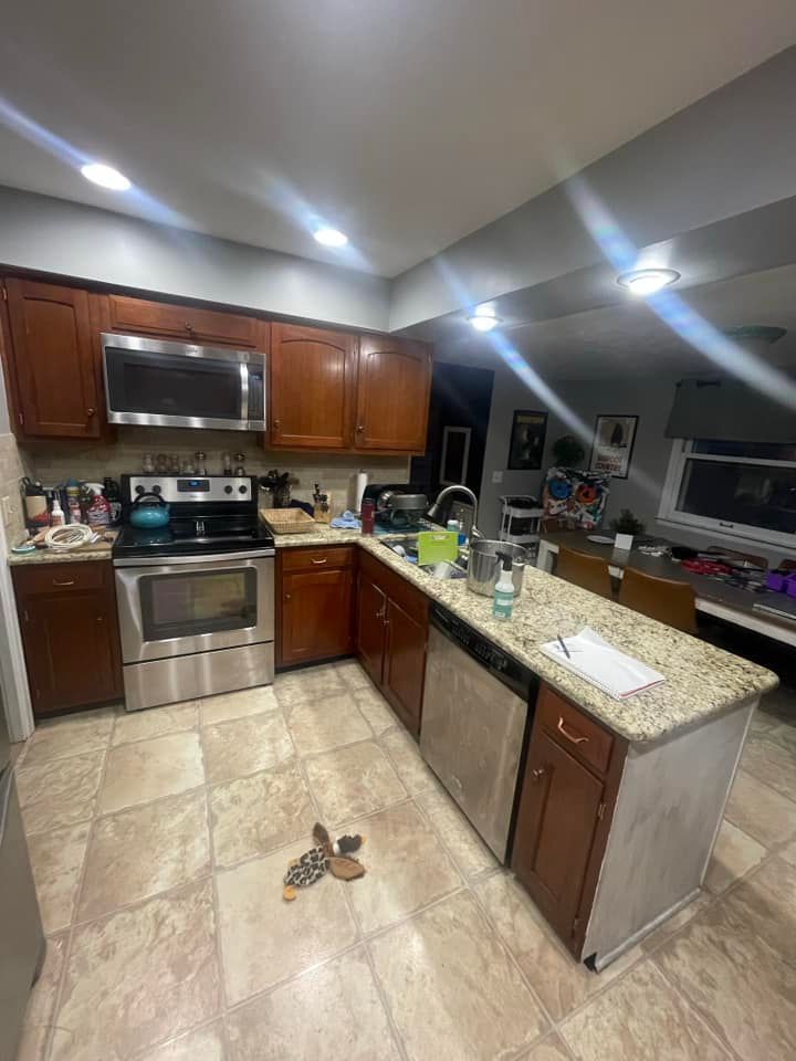 Kitchen with stainless steel appliances, brown cabinets, and a granite countertop island.